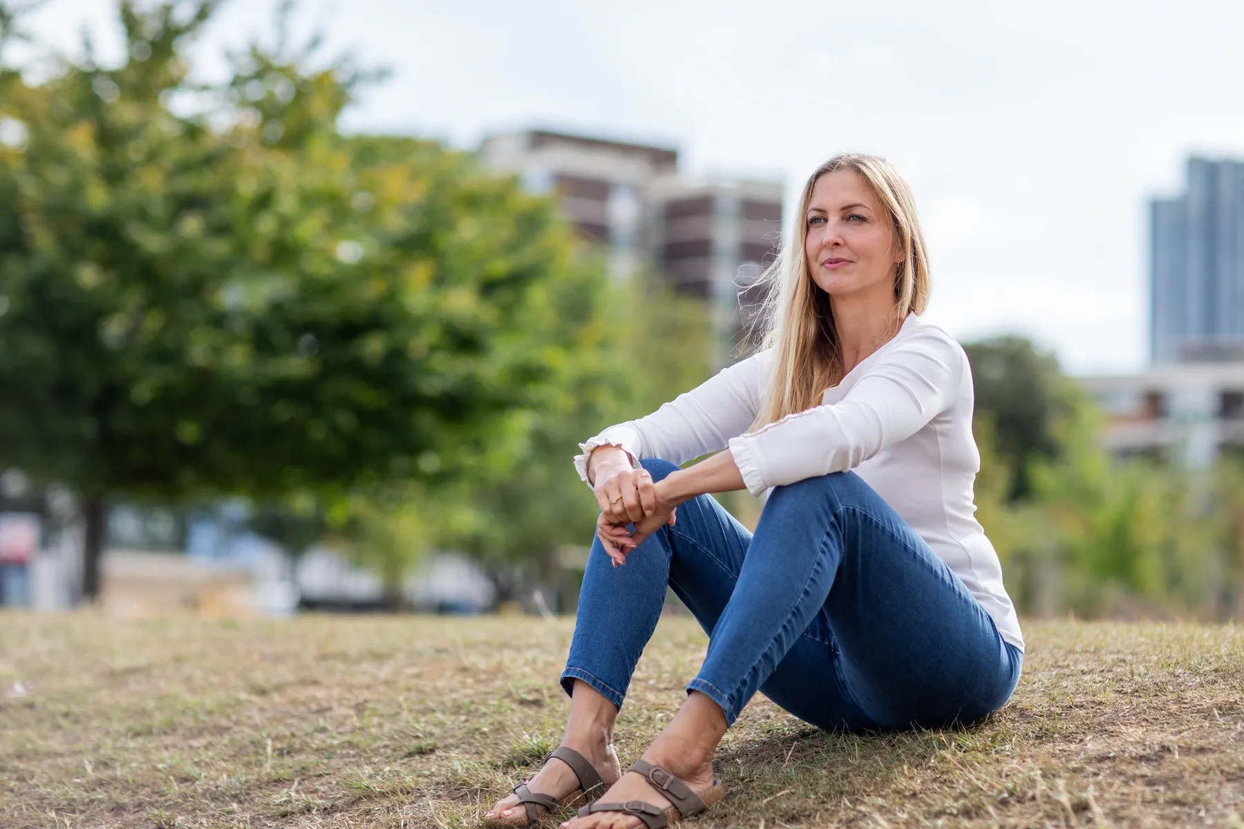 Maria Porsfelt sitting in a park, looking thoughtfully into the distance